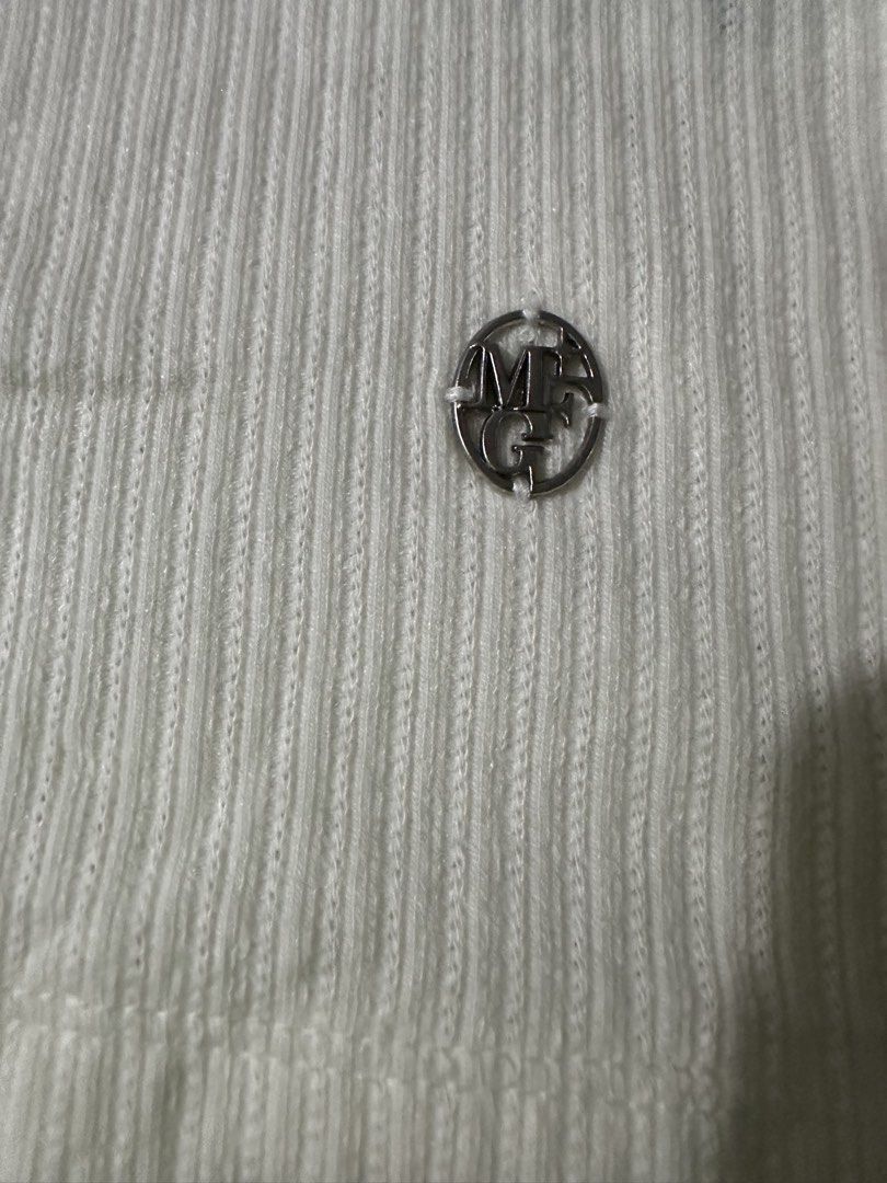 Marithe Francois Girbaud White Ribbed Tank Top Size S (Category: Sleeveless) located in Manila. Submitted by jessj30 (Listing ID 1460002276, Image 3). Description: - White ribbed tank top by Marithe Francois Girbaud - Features a small bow detail at the neckline - Subtle logo emblem on the front - Sleeveless design - Scalloped hem - Made from a comfortable cotton blend - Ideal basic piece for everyday outfits.