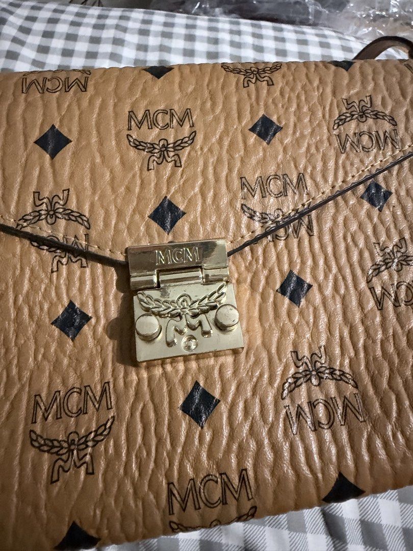 MCM Millie Flap Crossbody Bag (Category: Cross-body Bags) located in Manila. Submitted by prelovedbygayle (Listing ID 1460099900, Image 3). Description: Material & Design: Classic cognac coated canvas detailed with the repeating black MCM laurel logo and diamond pattern. Hardware: A front-facing Laurel Lock push-clasp closure engraved with the signature MCM brand name. Strap & Carry: Outfitted with a long, detachable cognac leather shoulder strap