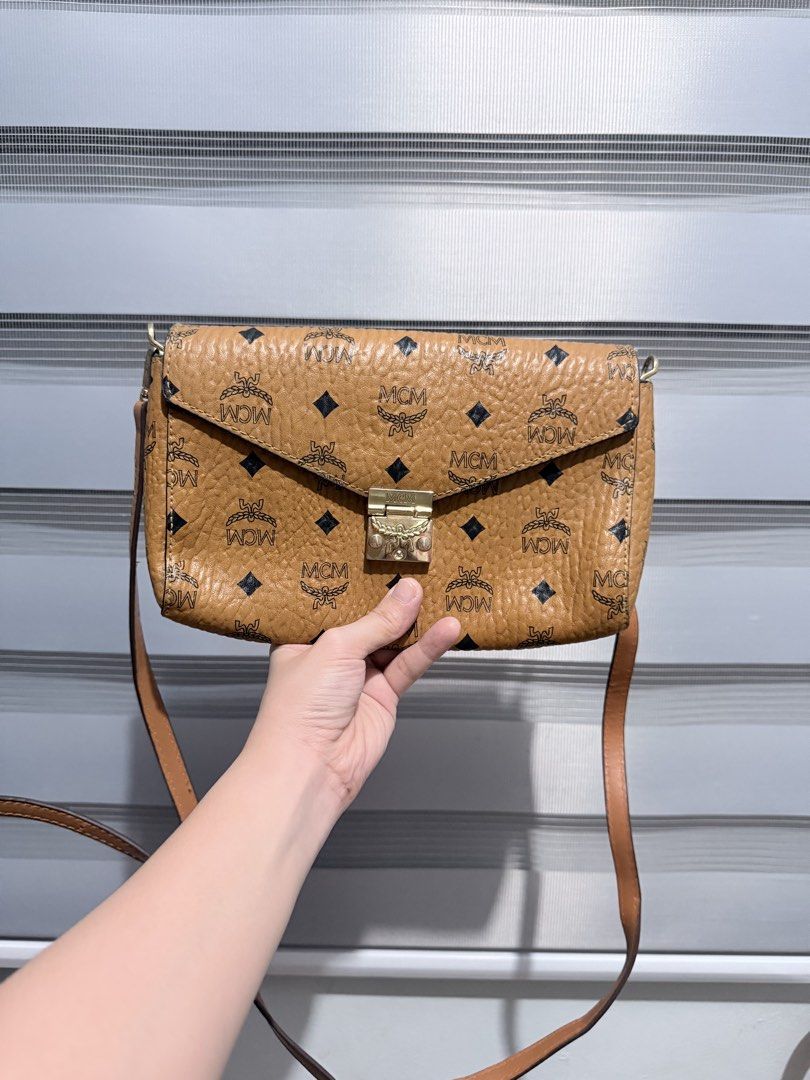 MCM Millie Flap Crossbody Bag (Category: Cross-body Bags) located in Manila. Submitted by prelovedbygayle (Listing ID 1460099900, Image 1). Description: Material & Design: Classic cognac coated canvas detailed with the repeating black MCM laurel logo and diamond pattern. Hardware: A front-facing Laurel Lock push-clasp closure engraved with the signature MCM brand name. Strap & Carry: Outfitted with a long, detachable cognac leather shoulder strap