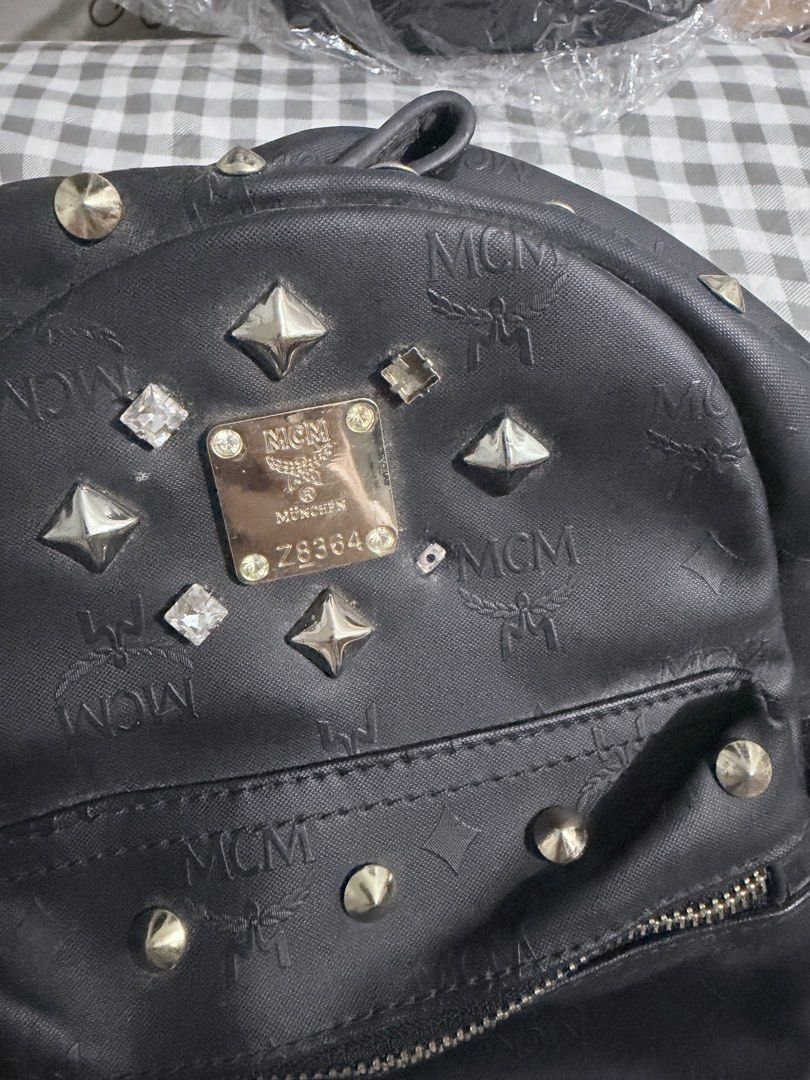 MCM Stark Studded Backpack (Category: Backpacks) located in Manila. Submitted by prelovedbygayle (Listing ID 1460099588, Image 3). Description: Material: Black Visetos monogram coated canvas with leather trim. Exterior Pockets: Front zipper compartment and dual flat side pockets. Hardware: Front panel detailed with a diamond-shaped stud configuration and an MCM branded metal plate. Straps: Adjustable canvas shoulder straps with a leather top hand