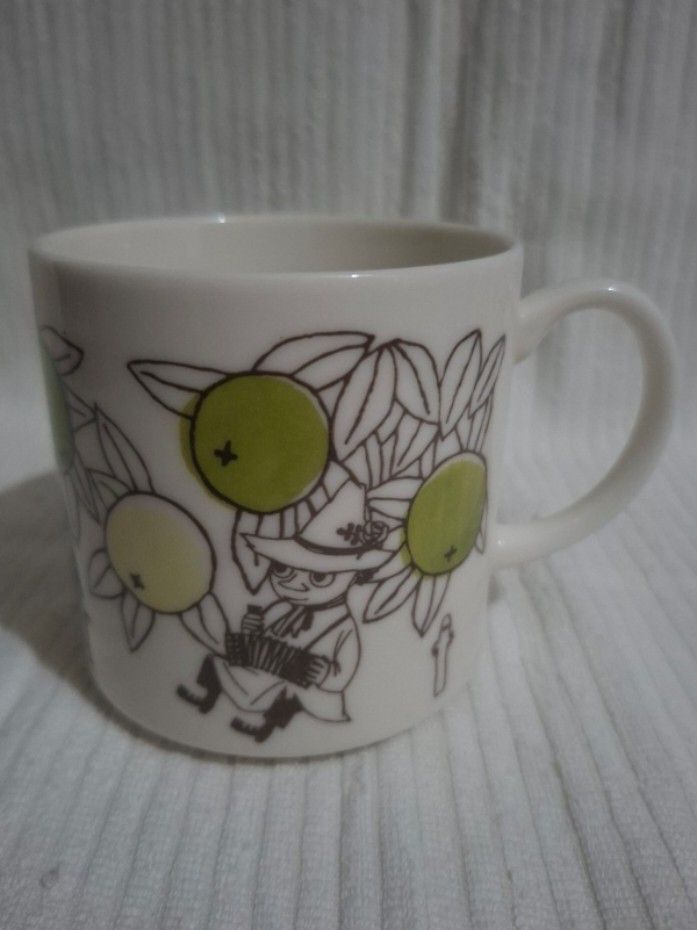 Moomin Characters Snufkin Mug by Yamaka (Category: Coffee & Tea Tableware) located in Consolacion. Submitted by luxekerei (Listing ID 1459900098, Image 1). Description: - white ceramic Moomin Characters Snufkin Ceramic Mug by Yamaka featuring green citrus fruit illustrations and Snufkin playing an accordion..
