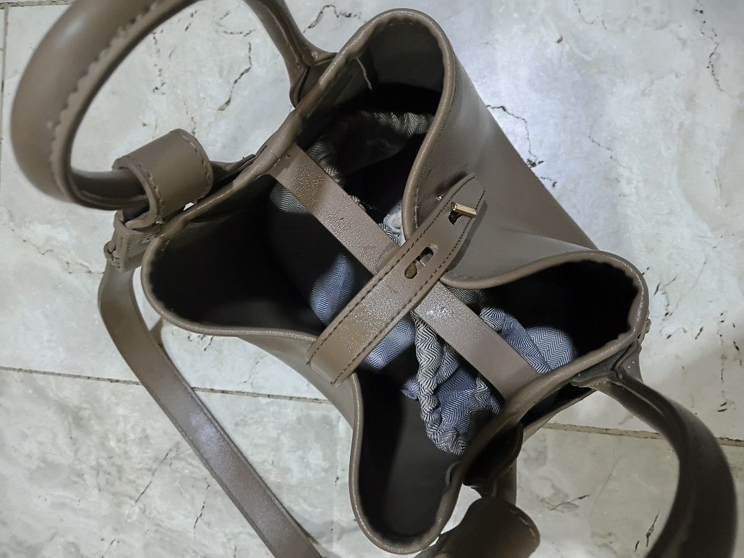 Mossdoom Taupe Bucket Bag with Shoulder Strap (Category: Shoulder Bags) located in Cavite. Submitted by ms.de.clutter (Listing ID 1460041757, Image 3). Description: - Stylish taupe bucket bag - Versatile: top handle and detachable shoulder strap - Elegant gold hardware details - Secure interior drawstring pouch - Ideal for everyday use and carrying essentials.