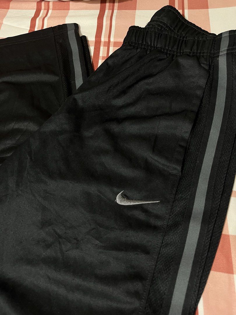 Nike Drifit Black Track Pants with Grey Stripes (Category: Joggers) located in Pasay City. Submitted by Oboyyy (Listing ID 1459793244, Image 2). Description: - Black Nike track pants - Iconic embroidered Nike swoosh logo on left leg - Two grey stripes down the sides of each leg - Comfortable elastic waistband - Ideal for sports or casual wear.