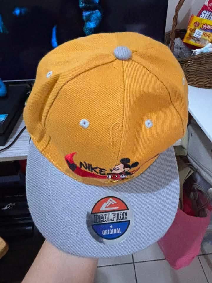 Nike Mickey Mouse & New York Yankees Caps Bundle (Category: Caps & Hats) located in Pasig City. Submitted by bookishnook (Listing ID 1460007003, Image 1). Description: - Two stylish snapback caps perfect for casual wear. - Cap 1: Vibrant yellow with a fun Nike and Mickey Mouse design. - Cap 2: Classic black with the iconic red New York Yankees logo and 'New York' text..