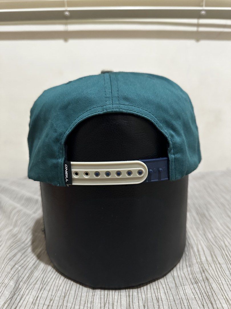 O'Neill California Snapback Cap (Category: Caps & Hats) located in Bacoor. Submitted by realbacktrack (Listing ID 1459905899, Image 3). Description: - Brand: O'Neill California - Style: Snapback Cap - Color: Dark green crown, light grey brim - Design: O'Neill logo with red lightning bolt graphic - Closure: Adjustable snapback - Material: 60% Cotton, 40% Polyester *needs wash (see pictures).