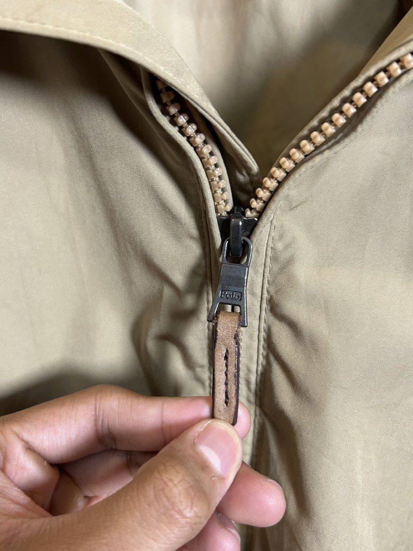 Polo Ralph Lauren Khaki yatch Jacket (Category: Coats, Jackets and Outerwear) located in Santa Ana. Submitted by thrift.sanctuary (Listing ID 1460051782, Image 3). Description: Classic khaki jacket from Polo Ralph Lauren. Features the iconic polo player logo embroidered on the chest. Zip-up front with a leather pull tab. Two front pockets with button closures. Striped detail on the inner collar. Great for layering..
