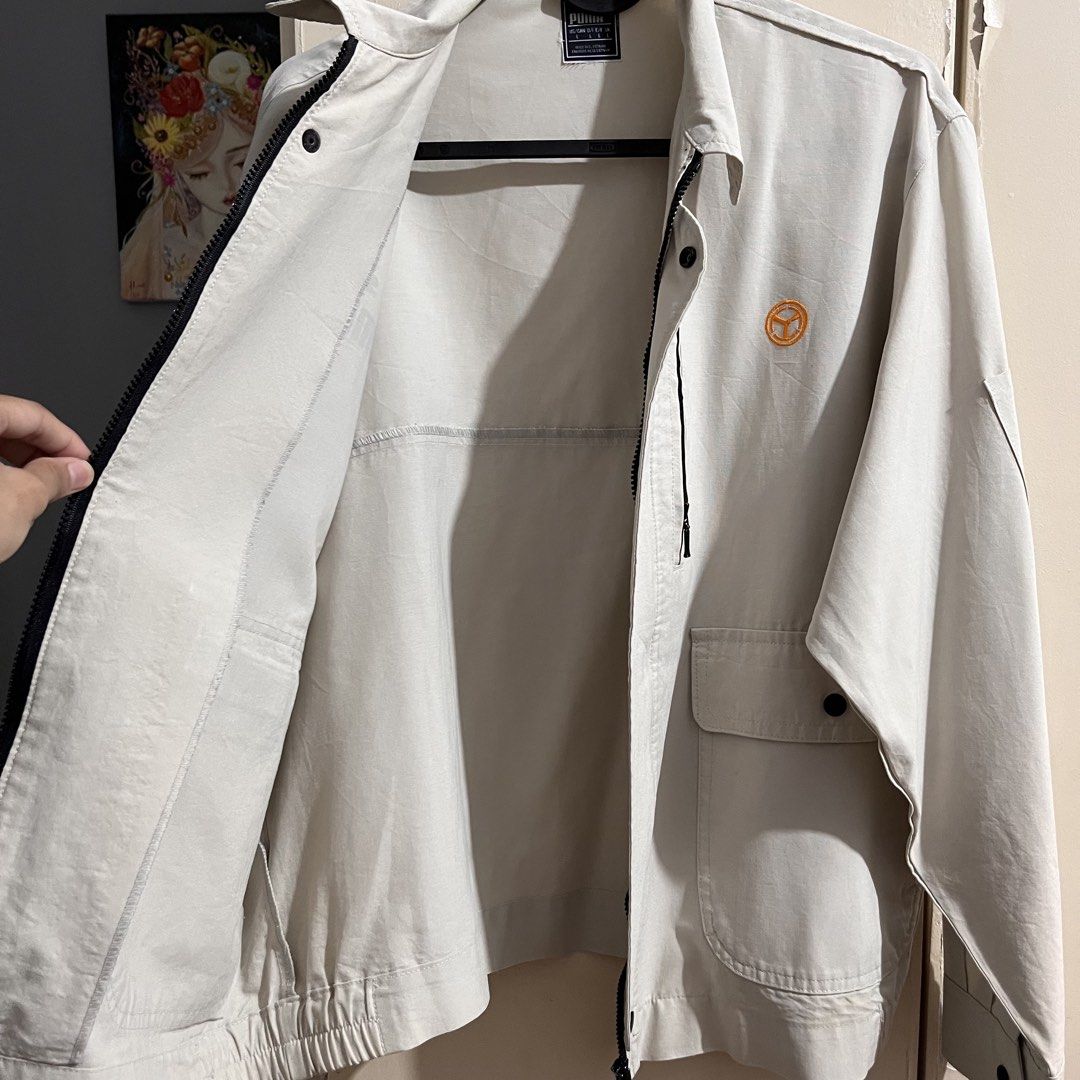 Puma Jacket L Beige Zip Up Utility Style (Category: Coats, Jackets and Outerwear) located in Makati City. Submitted by mikatamayo (Listing ID 1459939146, Image 3). Description: - Beige Puma Jacket - Size: Large (L) - Zip-up front closure - Multiple pockets for storage - Features a zippered chest pocket - Small, distinctive orange circular logo on the right chest - Made in Vietnam - Ideal for casual outfits or as a layering piece.