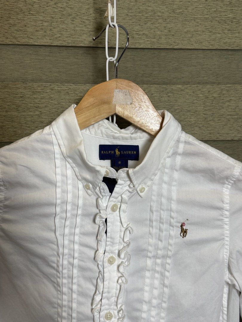 Ralph Lauren White Button Down Shirt Size 8 (Category: Tshirts & Polo Shirts ) located in Santa Ana. Submitted by thrift.sanctuary (Listing ID 1460082450, Image 2). Description: - White Ralph Lauren button down shirt - Size 8 - Ruffled front detail - Classic pony logo - Long sleeves with button cuffs - Versatile for dressing up or down.