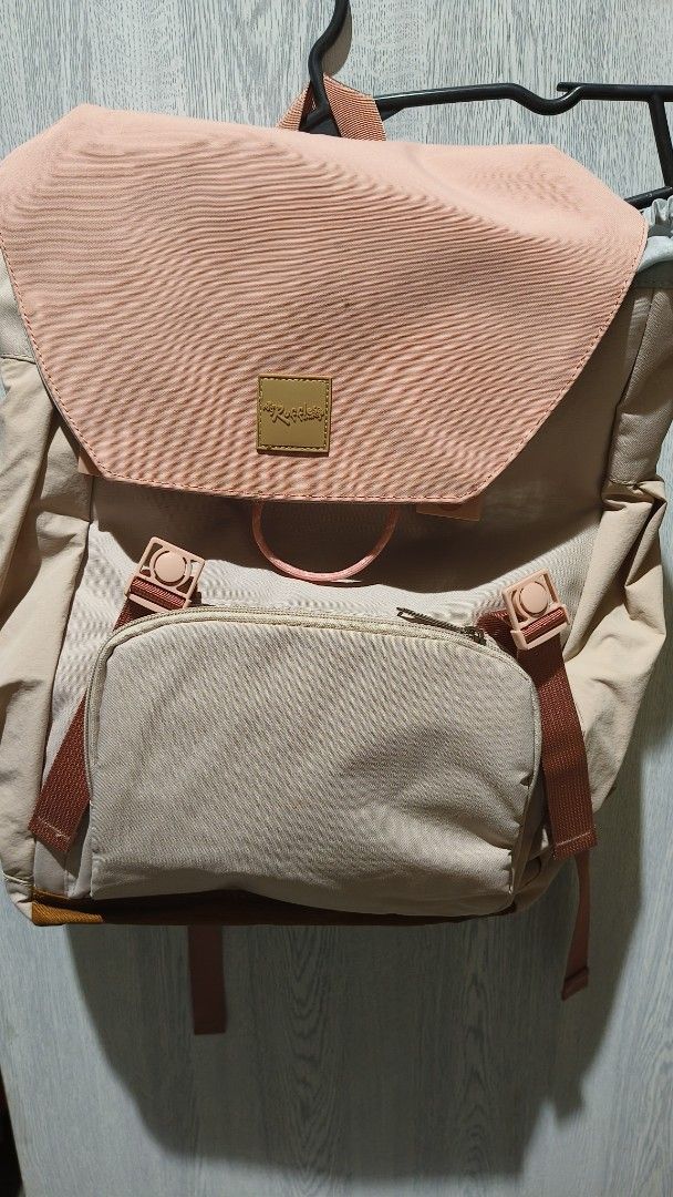 Roddle Backpack - Pink and Beige (Category: Backpacks) located in Manila. Submitted by eliana_marie (Listing ID 1459929265, Image 1). Description: - Cute beige backpack with a pink ribbed flap closure. - Front zip pocket for extra storage. - Adjustable straps for a comfortable fit. - Main flap is a stylish pink ribbed material. - Body of the bag is a light beige color. - Note: There is a small stain on the pink flap. - Ideal for school, work, or 