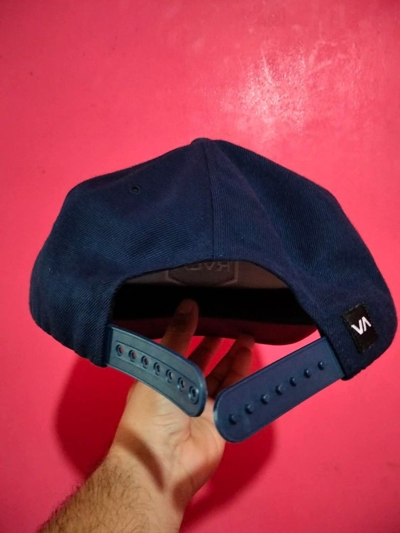 RVCA Snapback Cap Navy Blue Mid Fit (Category: Caps & Hats) located in Mangaldan. Submitted by niftythrifty69 (Listing ID 1459958538, Image 2). Description: - Navy blue RVCA snapback cap - Features the classic RVCA logo on the front - Adjustable strap at the back for a custom fit - 'Mid Fit' style - Perfect for everyday wear - Shows minimal signs of use.
