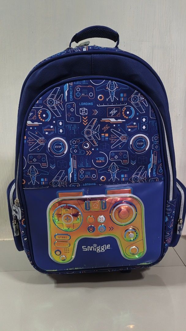 Smiggle Backpack with Light-Up Controller Design (Category: Strollers) located in Valenzuela. Submitted by ataraonlineshop (Listing ID 1459902212, Image 1). Description: - Cool Smiggle backpack for kids - Fun, light-up gaming controller design - Navy blue color - Multiple pockets and compartments - Wheels and pull-up handle for easy transport - Padded straps for comfort - Perfect for school or travel.