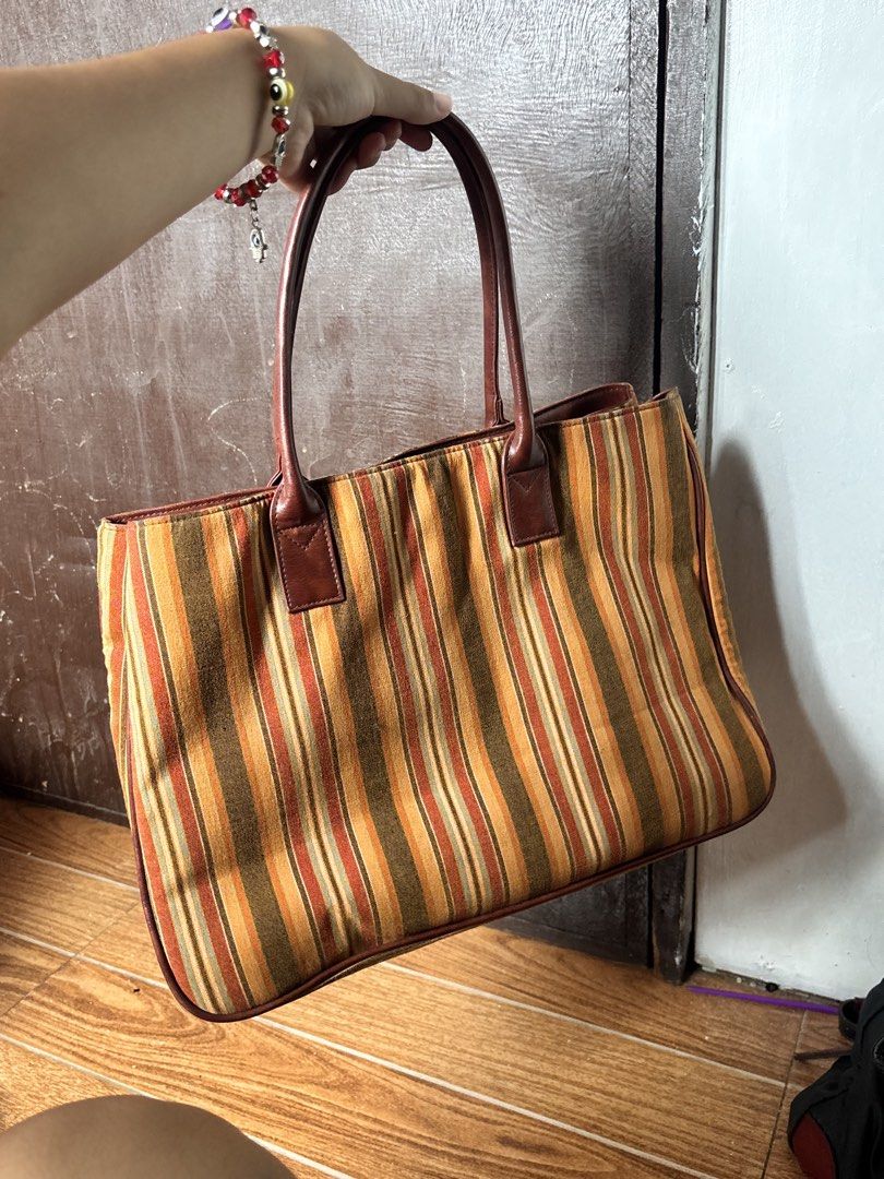 Striped Canvas Tote Bag with Leather Trim (Category: Tote Bags) located in Manila. Submitted by alyanarein (Listing ID 1459993269, Image 1). Description: Cute striped tote bag. Earthy tones with orange and brown stripes. Has leather handles and trim. Spacious enough for daily essentials. Great for casual outings or as a beach bag. Good condition, some minor signs of wear..