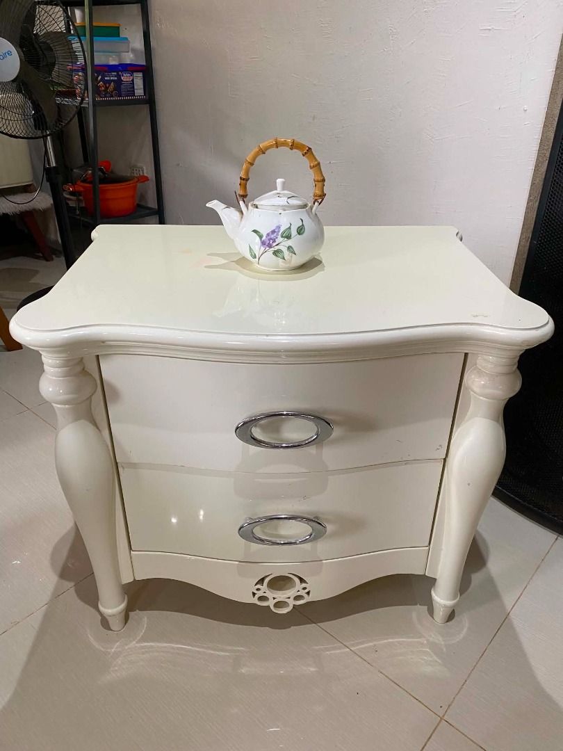 White 2-Drawer Nightstand with Chrome Handles (Category: Shelves, Cabinets & Racks) located in Minglanilla. Submitted by naquilagretchen (Listing ID 1460037396, Image 3). Description: - Chic white bedside table - Two spacious drawers for storage - Sleek chrome oval handles - Elegant curved, decorative legs - Unique circular detail at the bottom front - Perfect for keeping essentials within reach.