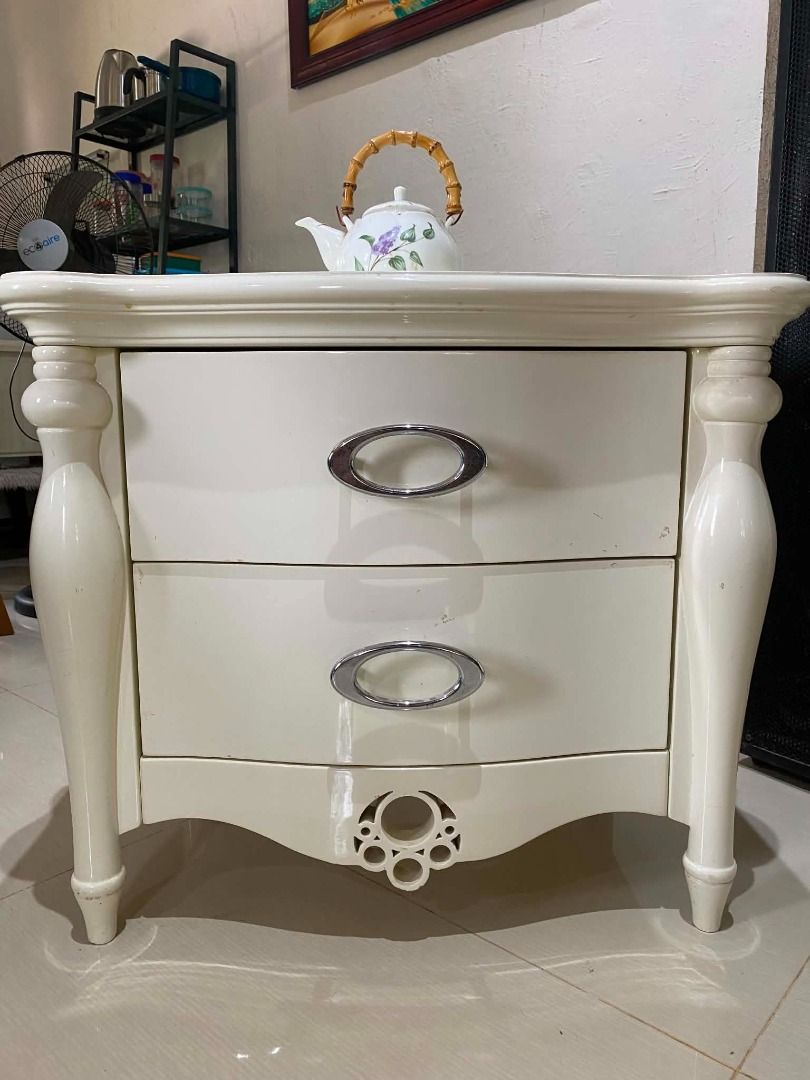 White 2-Drawer Nightstand with Chrome Handles (Category: Shelves, Cabinets & Racks) located in Minglanilla. Submitted by naquilagretchen (Listing ID 1460037396, Image 2). Description: - Chic white bedside table - Two spacious drawers for storage - Sleek chrome oval handles - Elegant curved, decorative legs - Unique circular detail at the bottom front - Perfect for keeping essentials within reach.