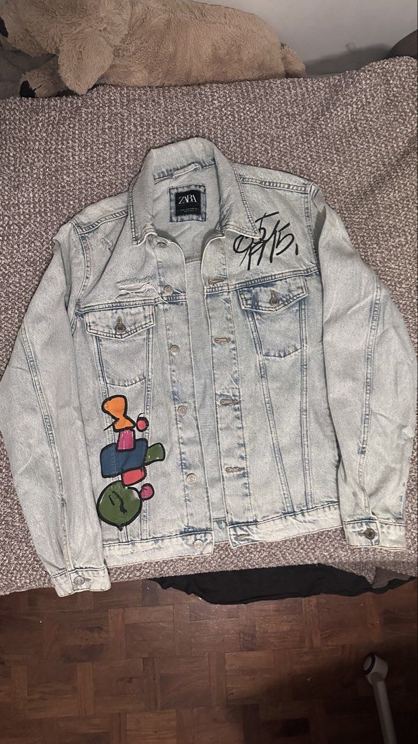 ZARA Light Wash Denim Jacket with Custom Art (Category: Coats, Jackets and Outerwear) located in Manila. Submitted by yuri0514 (Listing ID 1460058901, Image 1). Description: - ZARA light wash denim jacket - Custom graffiti-style art on front - Large abstract design on back - Distressed details on pockets and hem.