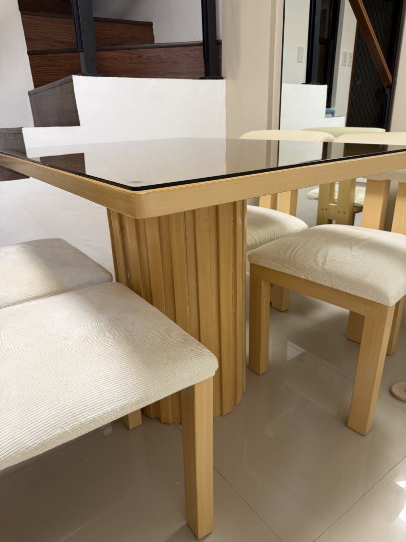 4-Seater Dining Set (Category: Tables & Sets) located in Rodriguez. Submitted by itschristinemunoz (Listing ID 1460198273, Image 2). Description: - Square glass top dining table - Sturdy wooden base - Includes 4 upholstered chairs - Chairs feature light-colored fabric seats - Cream-colored padded backrests - Ideal for small dining areas or kitchens - Ready for a new home.