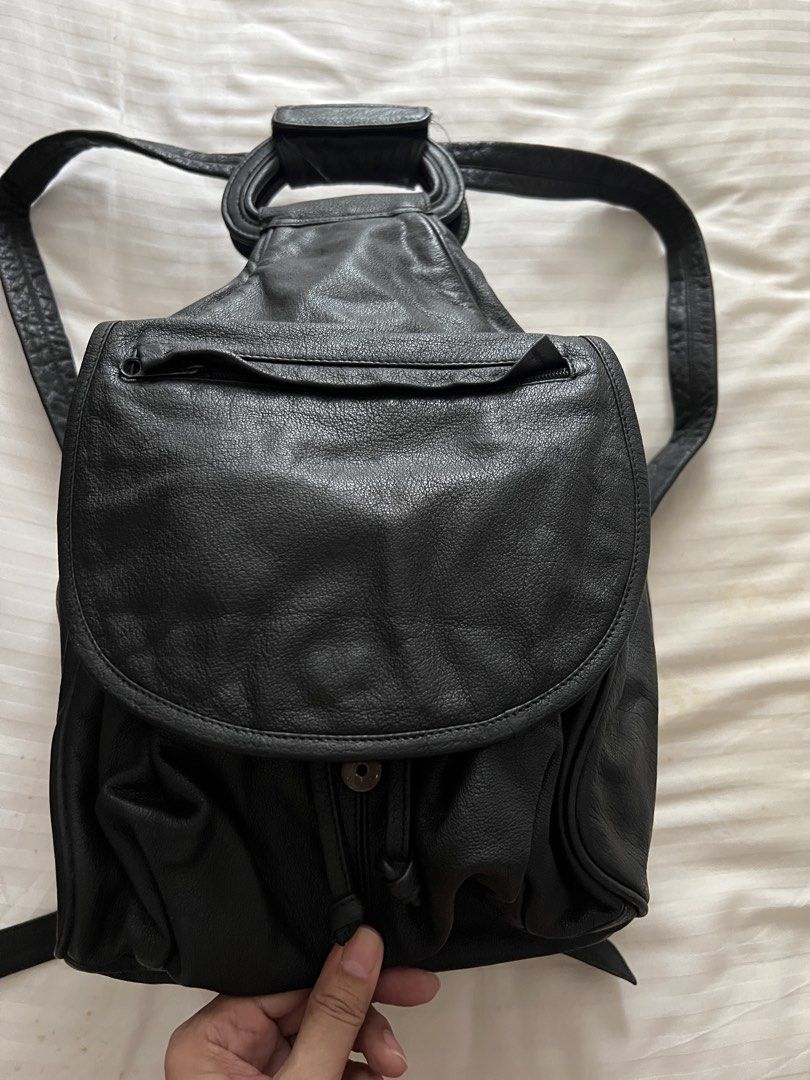 Black Leather Drawstring Backpack with Top Handle (Category: Backpacks) located in Pasig City. Submitted by jenscloset86 (Listing ID 1460167574, Image 1). Description: Brand: WILSON Material: Genuine Leather • see photos for some flaws. • some rust as seen in the photos. Measurement: Length: 9” Height: 16” Width: 9” - Genuine black leather backpack - Secure drawstring closure with button snap flap - Convenient front zip pocket - Sturdy top handle