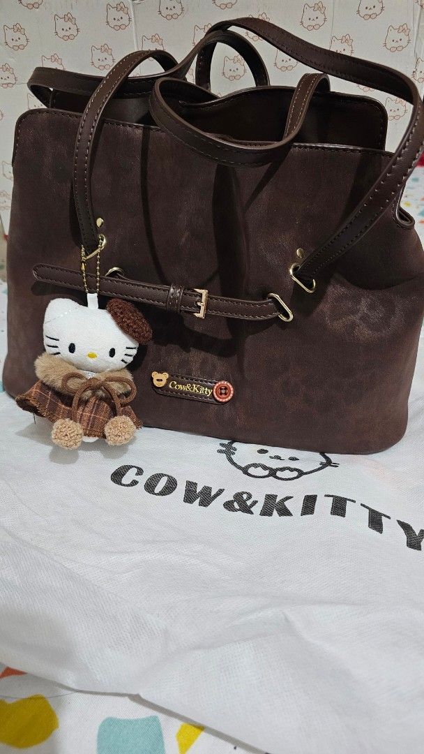Brown Cow & Kitty Drawstring Bag with Hello Kitty Charm (Category: Backpacks) located in Manila. Submitted by anatut (Listing ID 1460185651, Image 2). Description: - Cute brown drawstring bag - Adorable Kitty charm - Multiple interior compartments, including a zippered pocket - Adjustable straps for comfort - Secure buckle closure - Ideal for everyday use or as a fun accessory Used only twice. With box and dust bag. Bought on tiktok shop. Price i