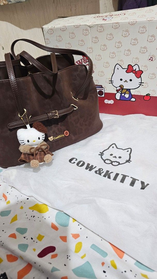 Brown Cow & Kitty Drawstring Bag with Hello Kitty Charm (Category: Backpacks) located in Manila. Submitted by anatut (Listing ID 1460185651, Image 1). Description: - Cute brown drawstring bag - Adorable Kitty charm - Multiple interior compartments, including a zippered pocket - Adjustable straps for comfort - Secure buckle closure - Ideal for everyday use or as a fun accessory Used only twice. With box and dust bag. Bought on tiktok shop. Price i