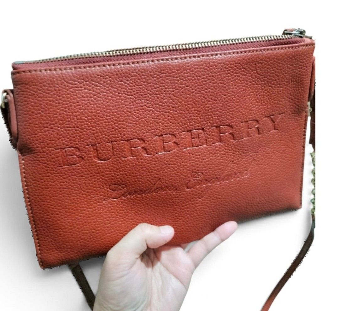 Auth Burberry Peyton Embossed Leather Crossbody Bag (Category: Luxury Bags & Wallets) located in Caloocan City. Submitted by almaeternamara (Listing ID 1460300229, Image 2). Description: Material: Premium grained calfskin leather providing a textured, scratch-resistant surface. Exterior Color: A rich rust orange/red shade accented with polished gold-tone hardware. Front Details: Prominently features the classic large embossed "BURBERRY" block let