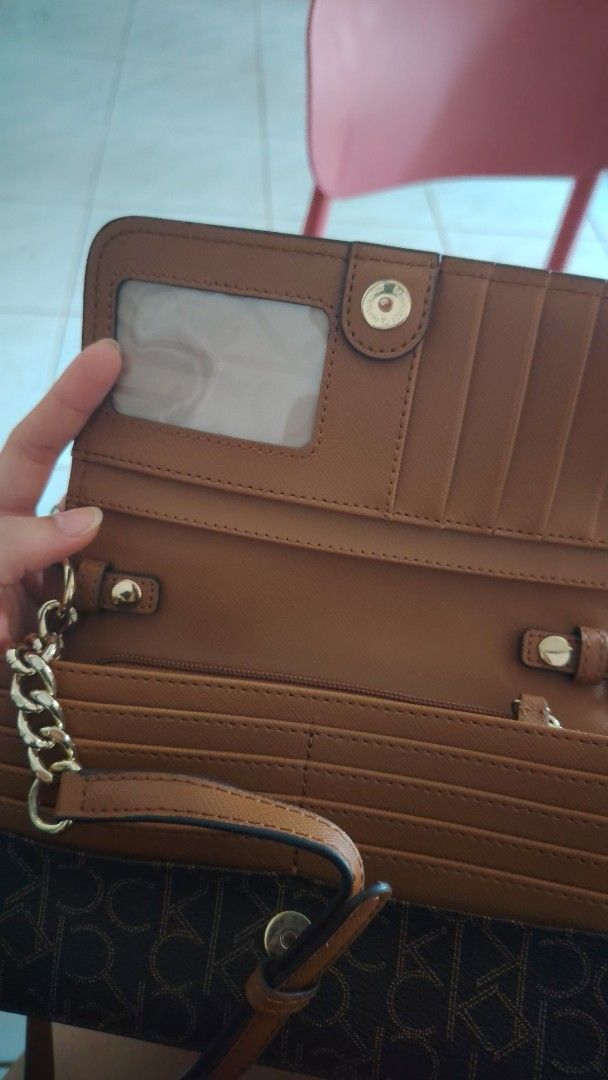 Calvin Klein Brown Wallet on Chain (Negotiable) (Category: Wallets & Card holders) located in Manila. Submitted by iamsaeemieese (Listing ID 1460198761, Image 1). Description: - Brown Calvin Klein wallet - Features iconic CK monogram print - Multiple card slots and a clear ID window - Detachable gold chain strap included - Secure snap closure - Versatile for everyday use or a night out.