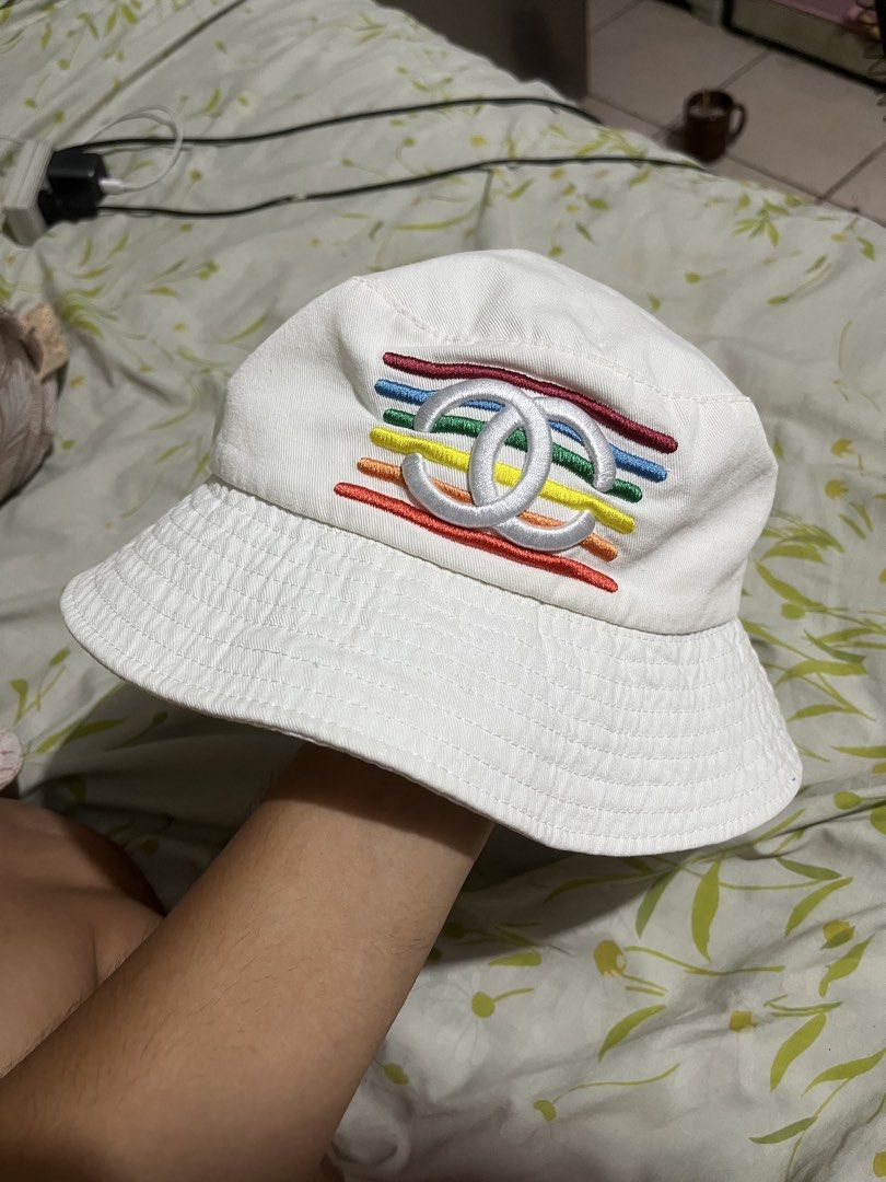 Chanel x Pharrell Williams White Bucket Hat (Category: Hats & Beanies) located in Pilar. Submitted by fast-flip-ni-miko. (Listing ID 1460274932, Image 2). Description: - White bucket hat - Red 'Chanel Pharrell' embroidery on one side - Iconic CC logo with rainbow stripes on the other side - Classic Chanel tag inside - Ideal for sunny days - A cool accessory to elevate any outfit.