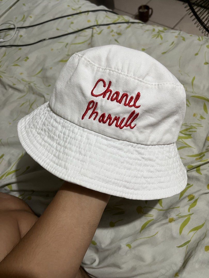 Chanel x Pharrell Williams White Bucket Hat (Category: Hats & Beanies) located in Pilar. Submitted by fast-flip-ni-miko. (Listing ID 1460274932, Image 1). Description: - White bucket hat - Red 'Chanel Pharrell' embroidery on one side - Iconic CC logo with rainbow stripes on the other side - Classic Chanel tag inside - Ideal for sunny days - A cool accessory to elevate any outfit.