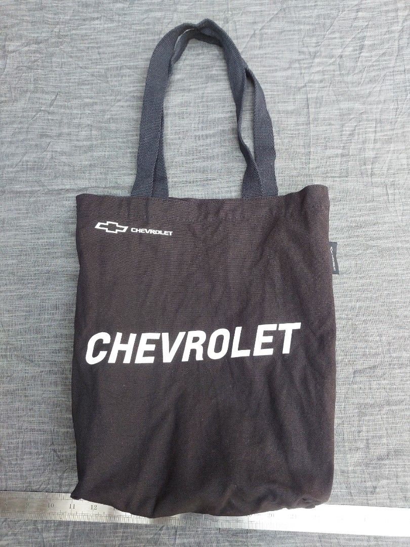 Chevrolet Tote Bag (Category: Tote Bags) located in Banga. Submitted by jahroldpan64406 (Listing ID 1460197837, Image 1). Description: - Black Chevrolet tote bag - Features Chevrolet logo and name on the front - Sturdy handles for comfortable carrying - Ideal for everyday use or casual shopping - A practical and stylish accessory for car enthusiasts.