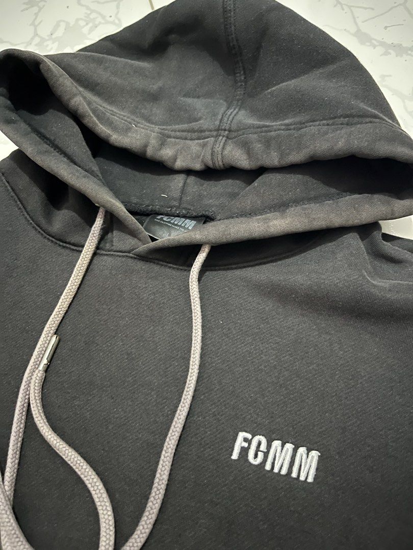 FCMM Black Hoodie Size L (Category: Coats, Jackets and Outerwear) located in Urdaneta. Submitted by supremo_fi (Listing ID 1460121900, Image 2). Description: - Issue: slight discoloration - Black FCMM hoodie - Size: Large (L) - Embroidered FCMM logo on chest - Grey drawstrings - Front kangaroo pocket - Ideal for casual outings.