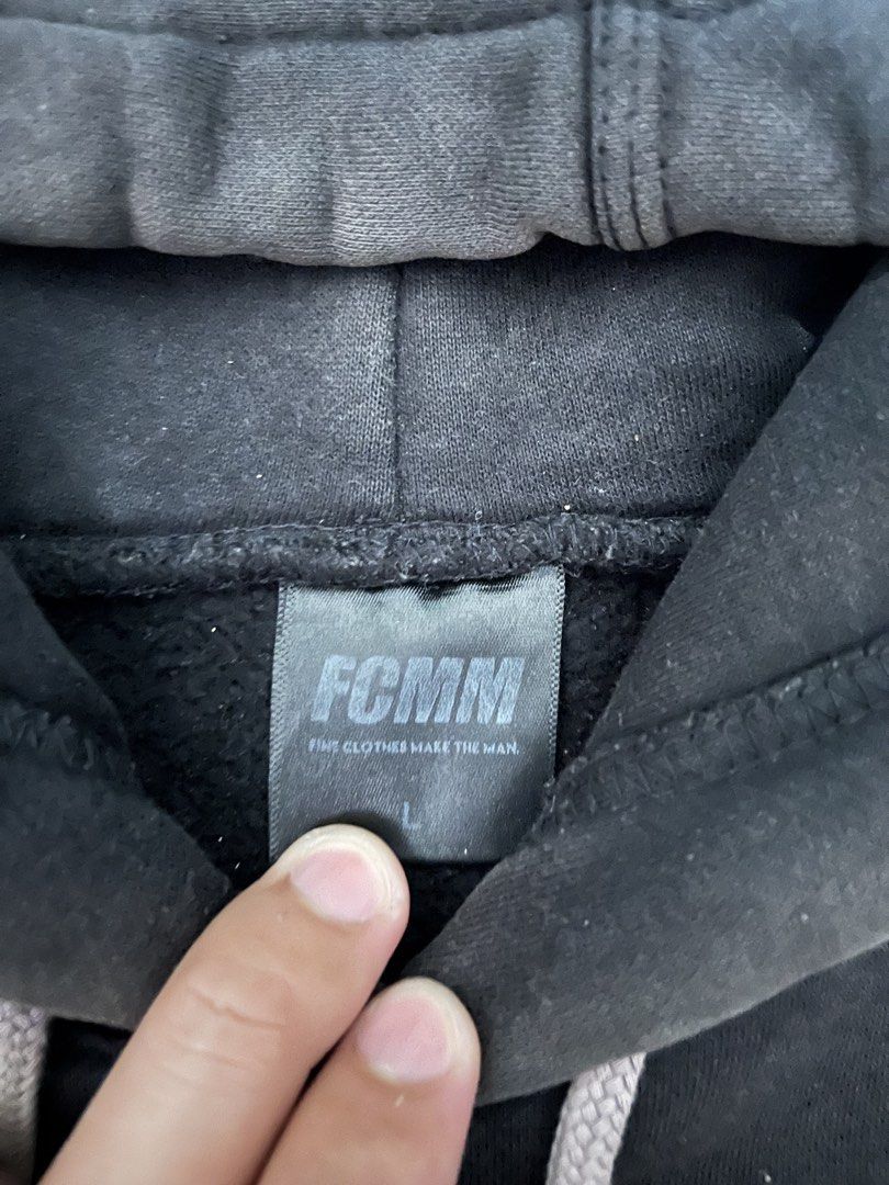 FCMM Black Hoodie Size L (Category: Coats, Jackets and Outerwear) located in Urdaneta. Submitted by supremo_fi (Listing ID 1460121900, Image 3). Description: - Issue: slight discoloration - Black FCMM hoodie - Size: Large (L) - Embroidered FCMM logo on chest - Grey drawstrings - Front kangaroo pocket - Ideal for casual outings.