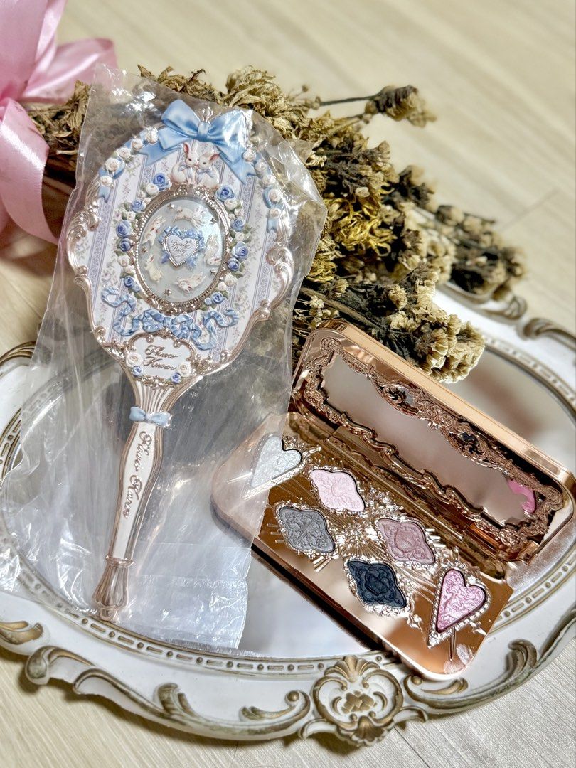 Flower Knows Mirror and Eyeshadow Palette Set (Category: Makeup) located in Manila. Submitted by truephoenix.fd5a21 (Listing ID 1460263826, Image 3). Description: - Adorable hand mirror with a charming blue ribbon and bunny design. - Brand new, still in its original packaging. - Includes a beautiful rose gold eyeshadow palette. - Palette features a mix of shimmery and matte shades. - Some eyeshadow pans are uniquely shaped like hearts. - Ideal fo