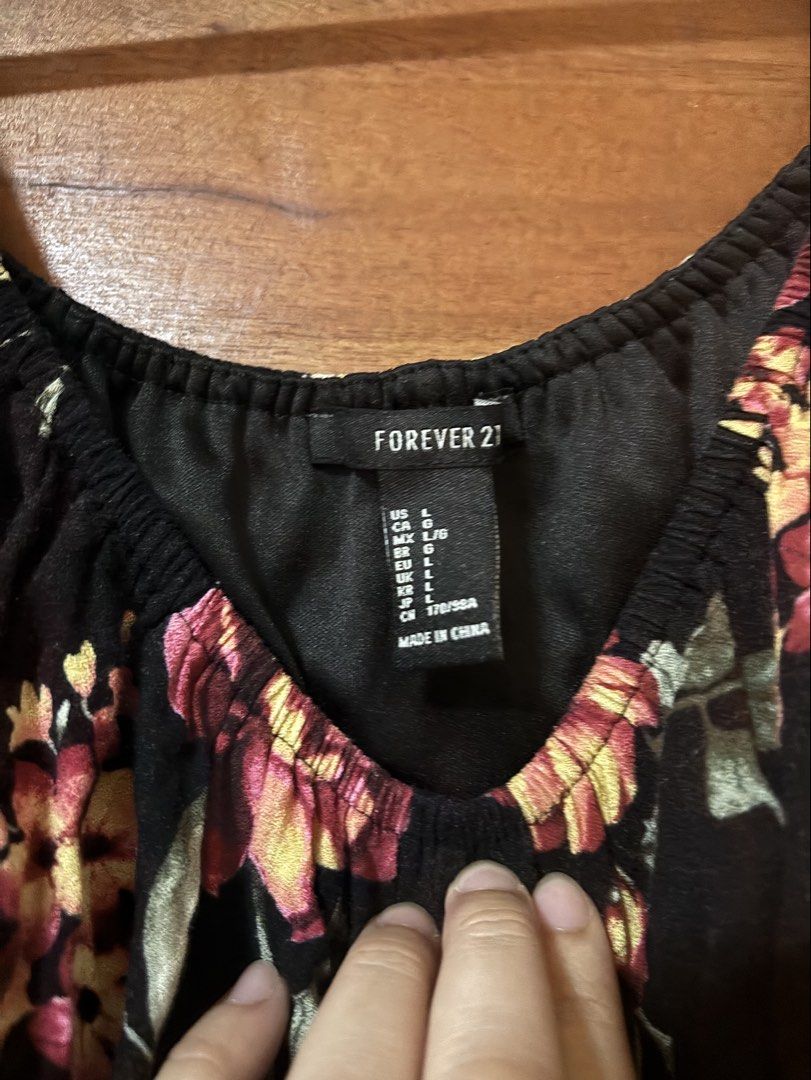 Forever 21 Black Floral Off-Shoulder Top (Category: Blouses) located in Trece Martires City. Submitted by decluttercloset_niks (Listing ID 1460298417, Image 2). Description: - Brand: Forever 21 - Style: Off-shoulder top - Color: Black with vibrant floral print (yellow & pink flowers) - Sleeves: Short with elasticated neckline - Material: Lightweight, ideal for warm weather - Size: L - Origin: Made in China.