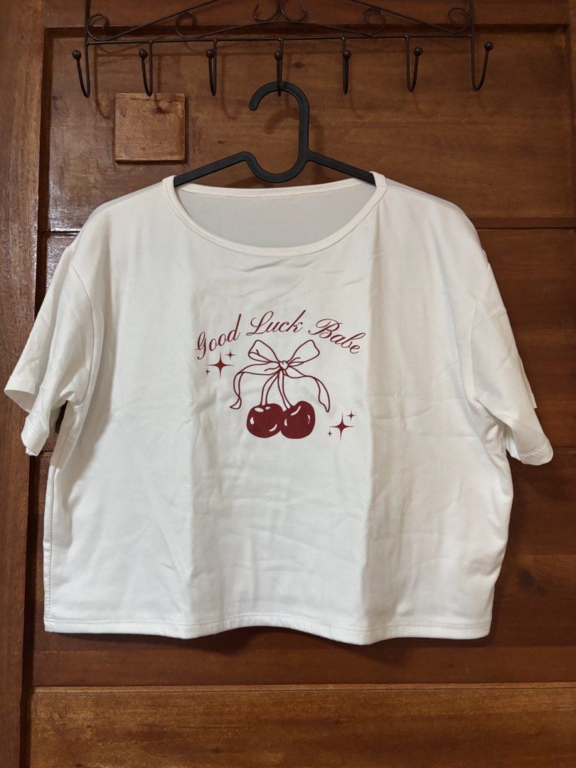 "Good Luck Babe" Cherry Graphic T-Shirt (Category: Shirts) located in Trece Martires City. Submitted by decluttercloset_niks (Listing ID 1460298547, Image 1). Description: - Cute white t-shirt - Features 'Good Luck Babe' graphic - Adorable cherry and bow design with subtle sparkle details - Short sleeves and classic crew neck - Relaxed fit for comfortable, casual wear.
