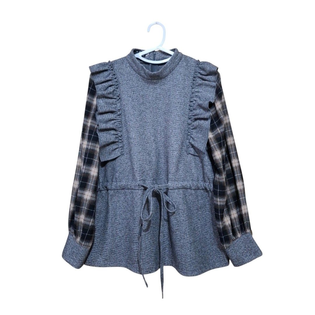 Grey Ruffle Mock Neck Plaid Sleeve Top (Category: Blouses) located in Pasig City. Submitted by m_r_g (Listing ID 1460237492, Image 1). Description: - Fits medium to semi large - Cozy grey top with a stylish mock neck - Features charming ruffle details down the front - Contrasting plaid sleeves add a unique touch - Adjustable drawstring waist for a perfect fit - Versatile for layering or wearing as a standalone piece.