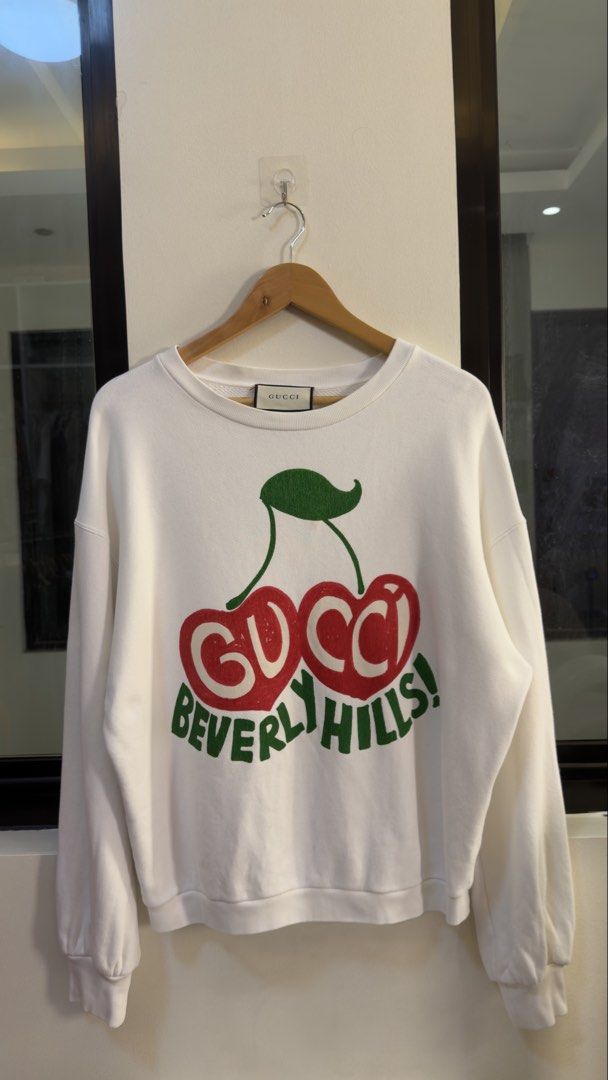 Gucci Beverly Hills Cherry Sweatshirt White (Category: Coats, Jackets and Outerwear) located in Paranaque City. Submitted by mykapoynton (Listing ID 1460293553, Image 2). Description: Gucci Beverly Hills Cherry Sweatshirt White - Iconic Cherry Print - Features 'Gucci Beverly Hills!' Text - Made in Italy - Size: Tagged XS (160/84Y) - Design: Crew neck, long sleeves - Style: Casual and stylish.
