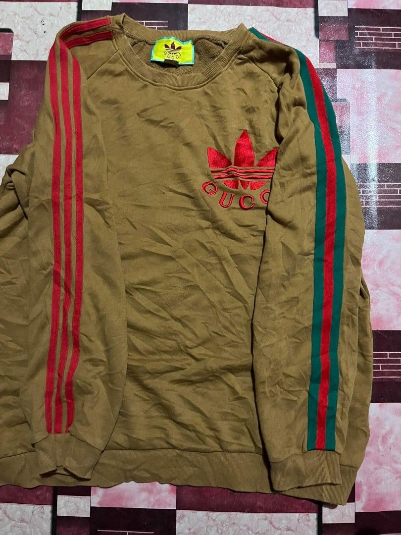Gucci x Adidas Brown Sweatshirt (Category: Coats, Jackets and Outerwear) located in Manila. Submitted by adzwilnams67005 (Listing ID 1460236643, Image 2). Description: - Authentic Gucci x Adidas collaboration sweatshirt - Size: XXL - Iconic Adidas red and green three stripes on sleeves - Embroidered red Gucci logo on the chest - Made in Italy - Excellent addition to any fashion collection Gucci x adidas ‎ ‎Size XXL on tag ‎Dimes:24.5x29 ‎Color ra