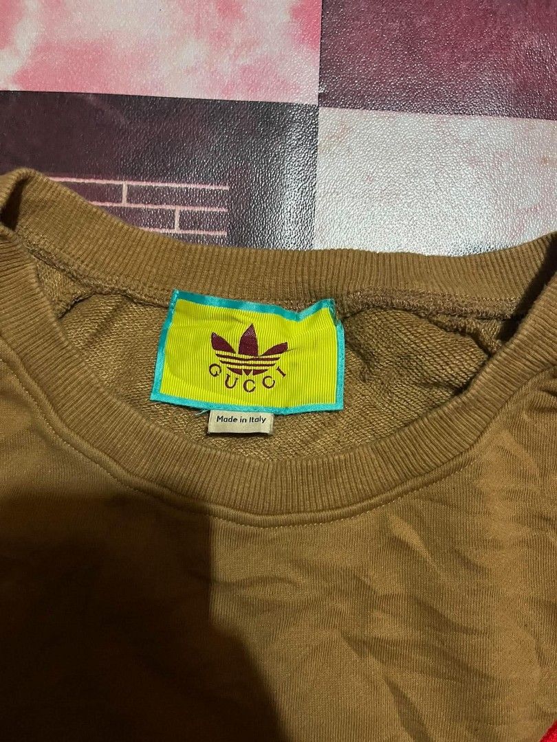 Gucci x Adidas Brown Sweatshirt (Category: Coats, Jackets and Outerwear) located in Manila. Submitted by adzwilnams67005 (Listing ID 1460236643, Image 3). Description: - Authentic Gucci x Adidas collaboration sweatshirt - Size: XXL - Iconic Adidas red and green three stripes on sleeves - Embroidered red Gucci logo on the chest - Made in Italy - Excellent addition to any fashion collection Gucci x adidas ‎ ‎Size XXL on tag ‎Dimes:24.5x29 ‎Color ra