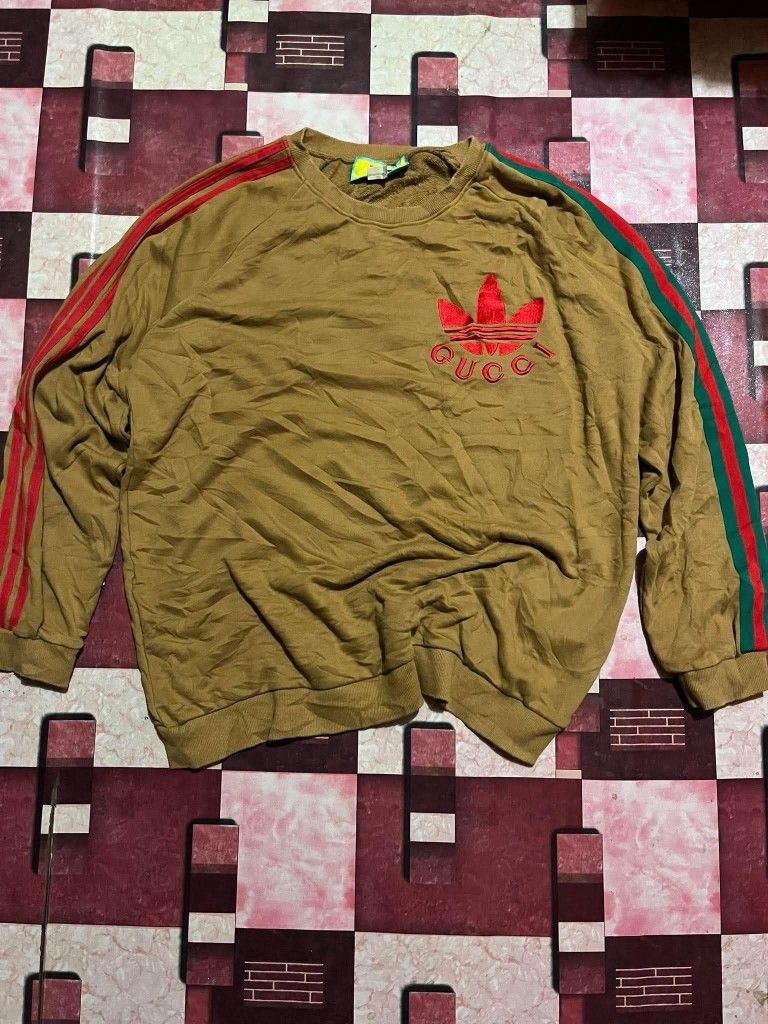 Gucci x Adidas Brown Sweatshirt (Category: Coats, Jackets and Outerwear) located in Manila. Submitted by adzwilnams67005 (Listing ID 1460236643, Image 1). Description: - Authentic Gucci x Adidas collaboration sweatshirt - Size: XXL - Iconic Adidas red and green three stripes on sleeves - Embroidered red Gucci logo on the chest - Made in Italy - Excellent addition to any fashion collection Gucci x adidas ‎ ‎Size XXL on tag ‎Dimes:24.5x29 ‎Color ra