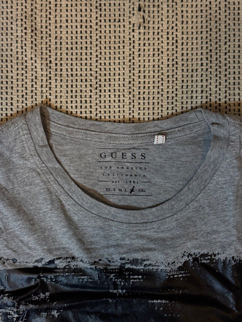 Guess Los Angeles Graphic Tee Grey (Category: Tshirts & Polo Shirts ) located in Manila. Submitted by juddscloset (Listing ID 1460249791, Image 3). Description: Guess Los Angeles graphic t-shirt, grey, distressed-print black triangle/text design on front. Preloved, from my own closet. Measured: Chest 50cm flat (~19.7” / ~39.4” circumference) | Length 68cm (~26.8”) | Sleeve opening 17cm flat (~6.7”).