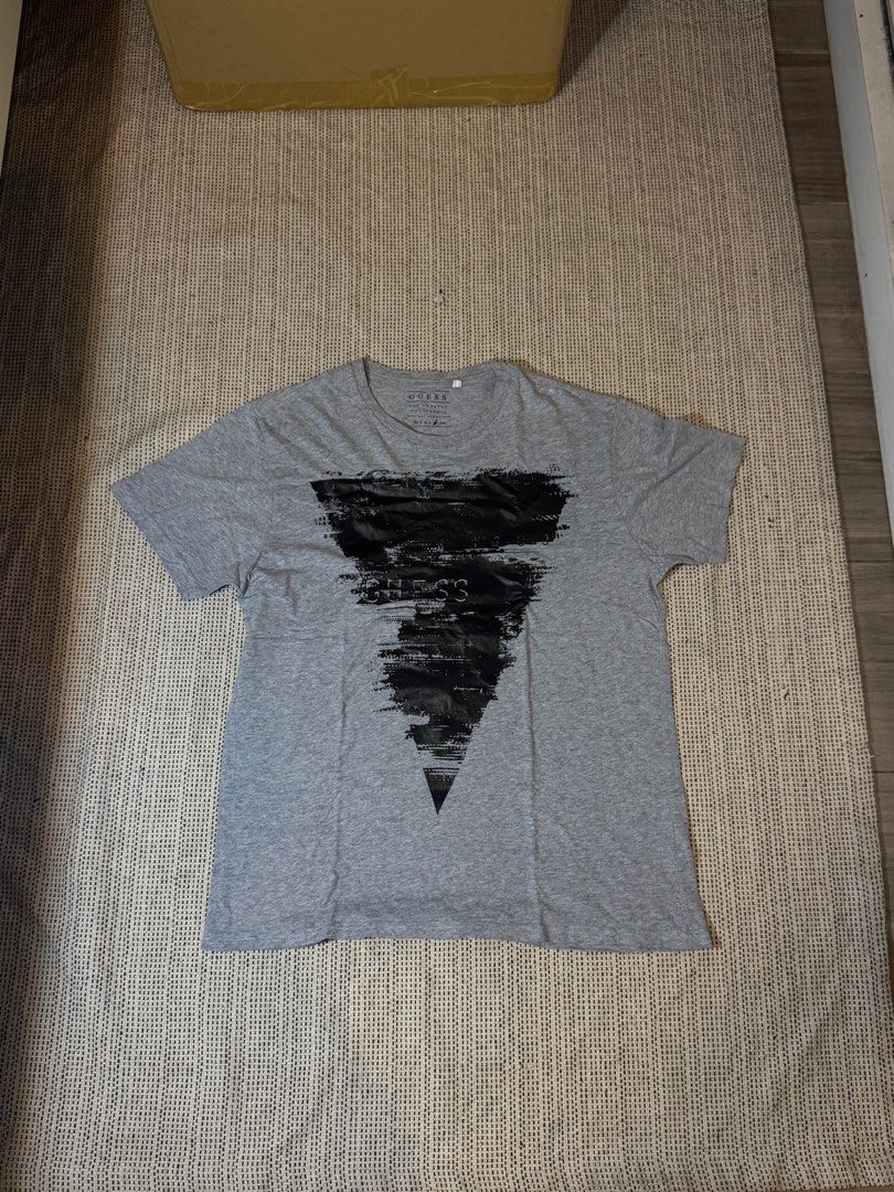 Guess Los Angeles Graphic Tee Grey (Category: Tshirts & Polo Shirts ) located in Manila. Submitted by juddscloset (Listing ID 1460249791, Image 1). Description: Guess Los Angeles graphic t-shirt, grey, distressed-print black triangle/text design on front. Preloved, from my own closet. Measured: Chest 50cm flat (~19.7” / ~39.4” circumference) | Length 68cm (~26.8”) | Sleeve opening 17cm flat (~6.7”).