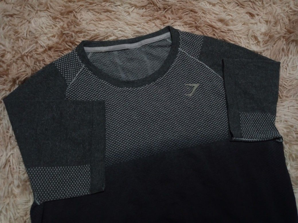 Gymshark Seamless T-shirt (Category: Activewear) located in Boston. Submitted by johnpaulvi30029 (Listing ID 1460242385, Image 3). Description: - Gymshark seamless t-shirt - Color: Dark grey and black gradient - Features breathable knit pattern on chest and back - Short sleeves - Ideal for workouts or casual wear - Comfortable and lightweight material.