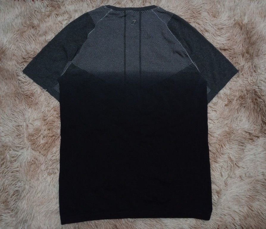 Gymshark Seamless T-shirt (Category: Activewear) located in Boston. Submitted by johnpaulvi30029 (Listing ID 1460242385, Image 2). Description: - Gymshark seamless t-shirt - Color: Dark grey and black gradient - Features breathable knit pattern on chest and back - Short sleeves - Ideal for workouts or casual wear - Comfortable and lightweight material.