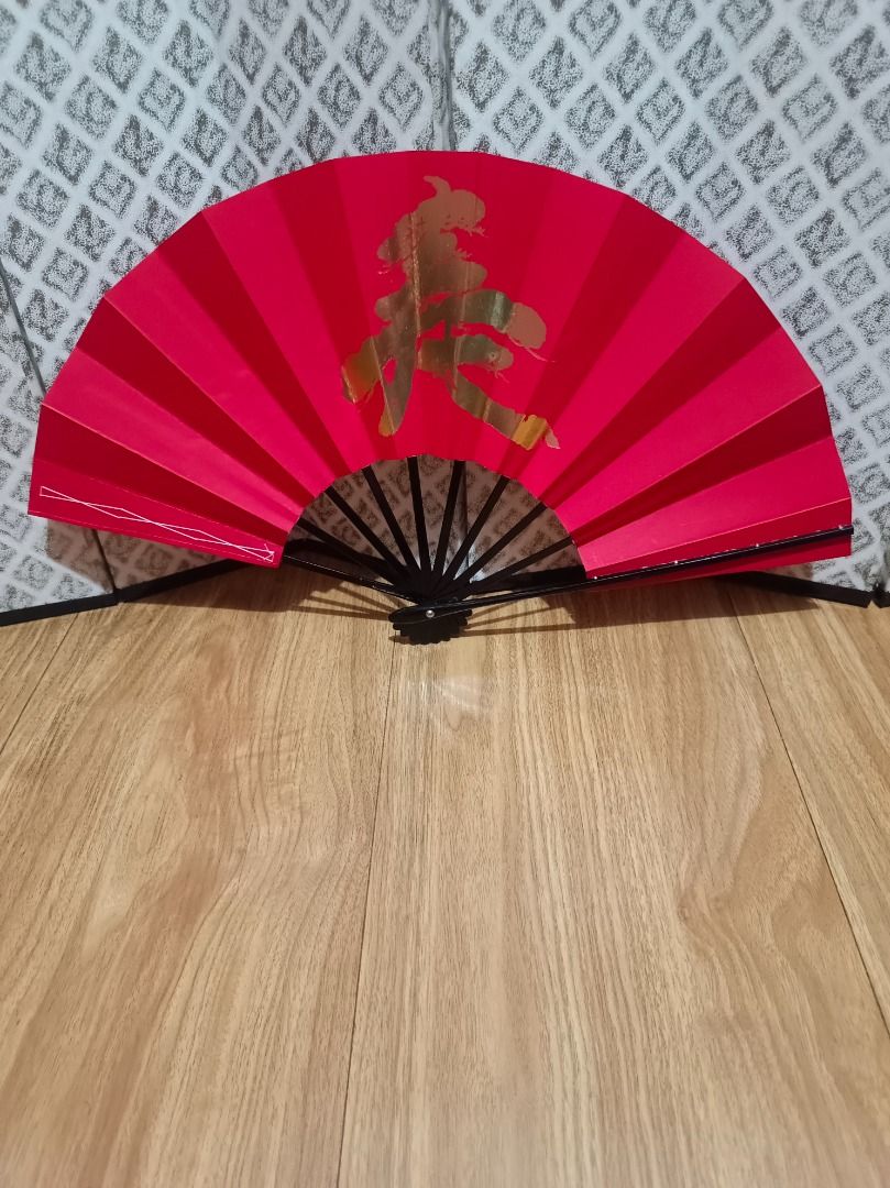 Japanese Traditional Paper Fan (Category: Fans) located in Makati City. Submitted by nyxhemera26 (Listing ID 1460168748, Image 2). Description: Japanese Traditional Paper Fan - Elegant red folding fan - Features a gold Chinese character symbolizing 'spring' - Sturdy black handle - Compact and portable when folded - Ideal for home decor or personal cooling - A festive addition for Chinese New Year celebrations.