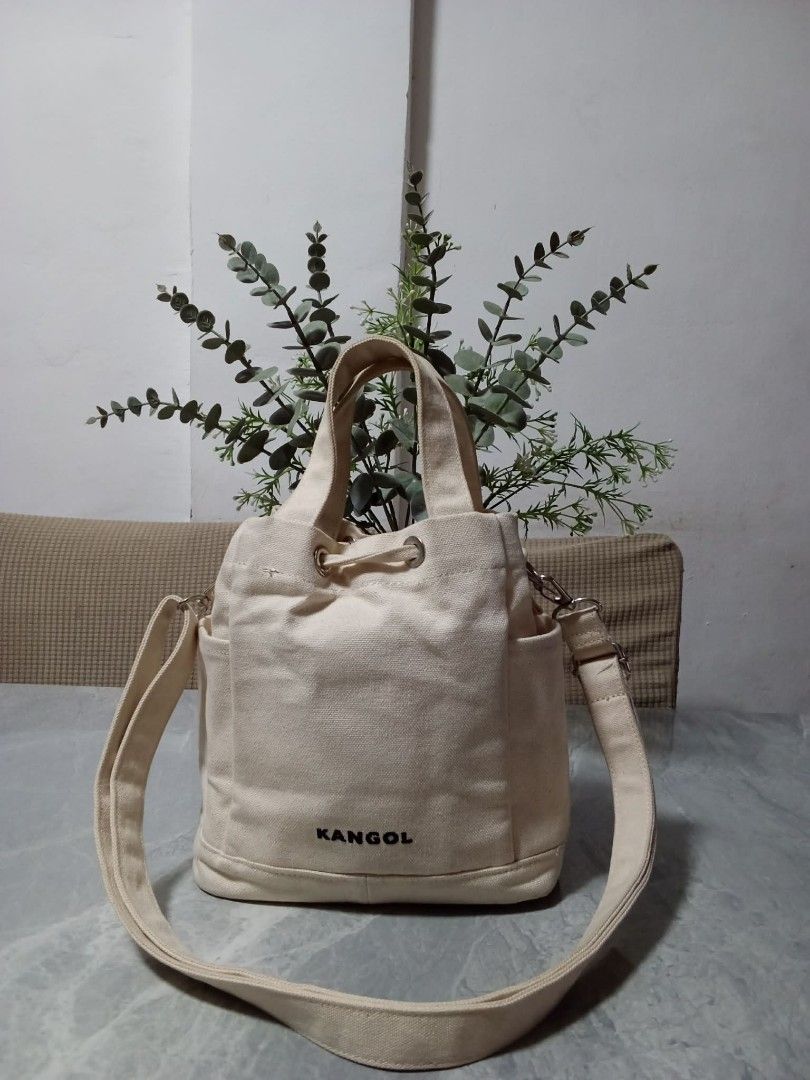 Kangol Canvas Bucket Bag Cream (Category: Cross-body Bags) located in Manila. Submitted by cosmiccloud-9236 (Listing ID 1460207873, Image 2). Description: - Cream colored canvas bucket bag from Kangol - Features a drawstring closure - Includes a detachable shoulder strap - Also has top handles for versatile carrying - Two convenient side pockets - Simple and classic design, ideal for everyday use.