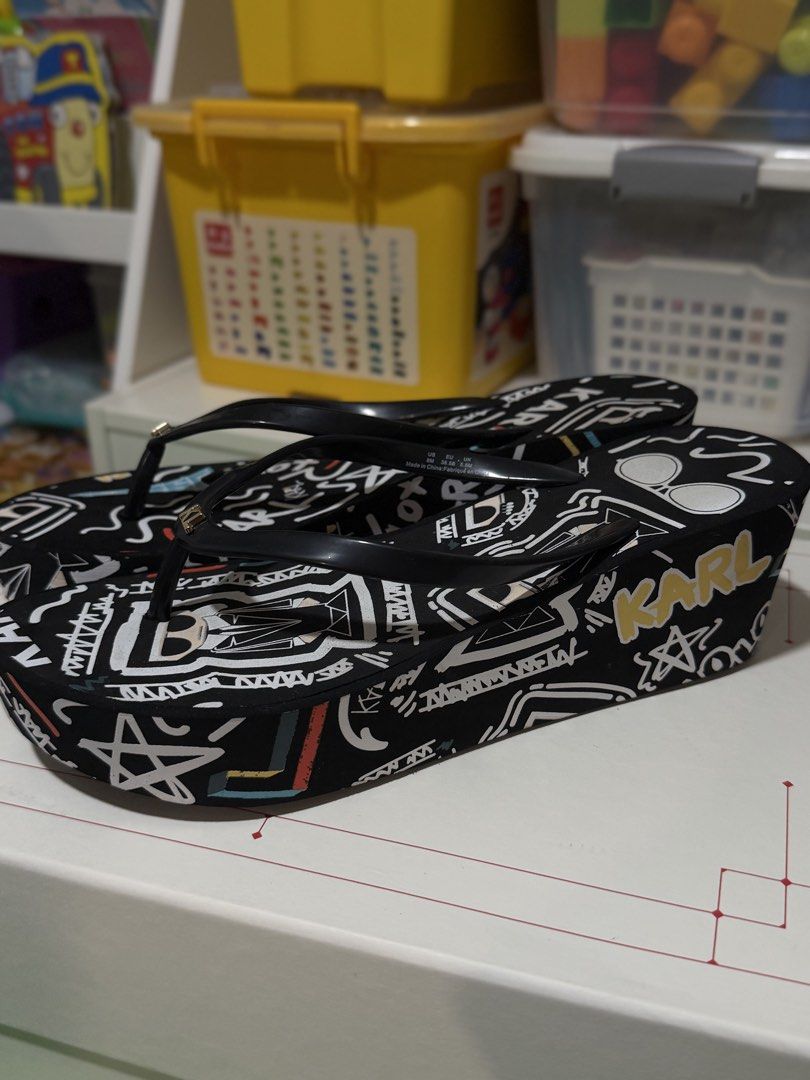 Karl Lagerfeld Black Graffiti Wedge Flip Flops (Category: Slippers and slides) located in Marikina City. Submitted by sisbasco999 (Listing ID 1460290707, Image 3). Description: - Authentic Karl Lagerfeld wedge flip flops - Stylish black with a vibrant graffiti print - Features the iconic KL logo on the straps - Comfortable platform sole for a subtle lift - Ideal for beach days or everyday casual wear - Unique and eye-catching design.