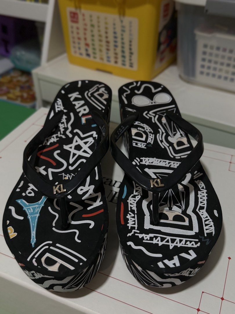 Karl Lagerfeld Black Graffiti Wedge Flip Flops (Category: Slippers and slides) located in Marikina City. Submitted by sisbasco999 (Listing ID 1460290707, Image 2). Description: - Authentic Karl Lagerfeld wedge flip flops - Stylish black with a vibrant graffiti print - Features the iconic KL logo on the straps - Comfortable platform sole for a subtle lift - Ideal for beach days or everyday casual wear - Unique and eye-catching design.