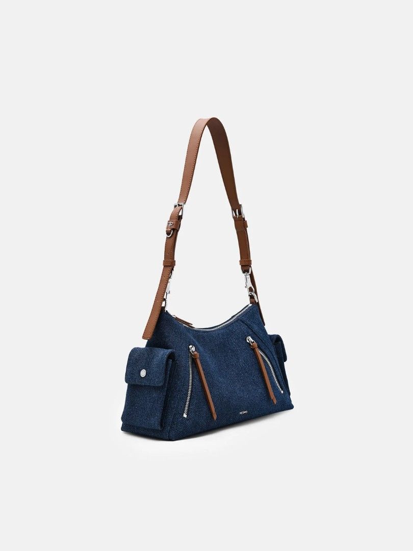 Kristen Denim Shoulder Bag - Blue Denim (Category: Announcements) located in Makati City. Submitted by zoeppe_online (Listing ID 1460298764, Image 2). Description: Defined by a utilitarian-inspired aesthetic, this slouchy shoulder bag is punctuated by functional zip details and structured side pockets. It features a wide, adjustable strap with polished hardware for a customizable fit. A contemporary take on the carry-all, balancing tactile softne