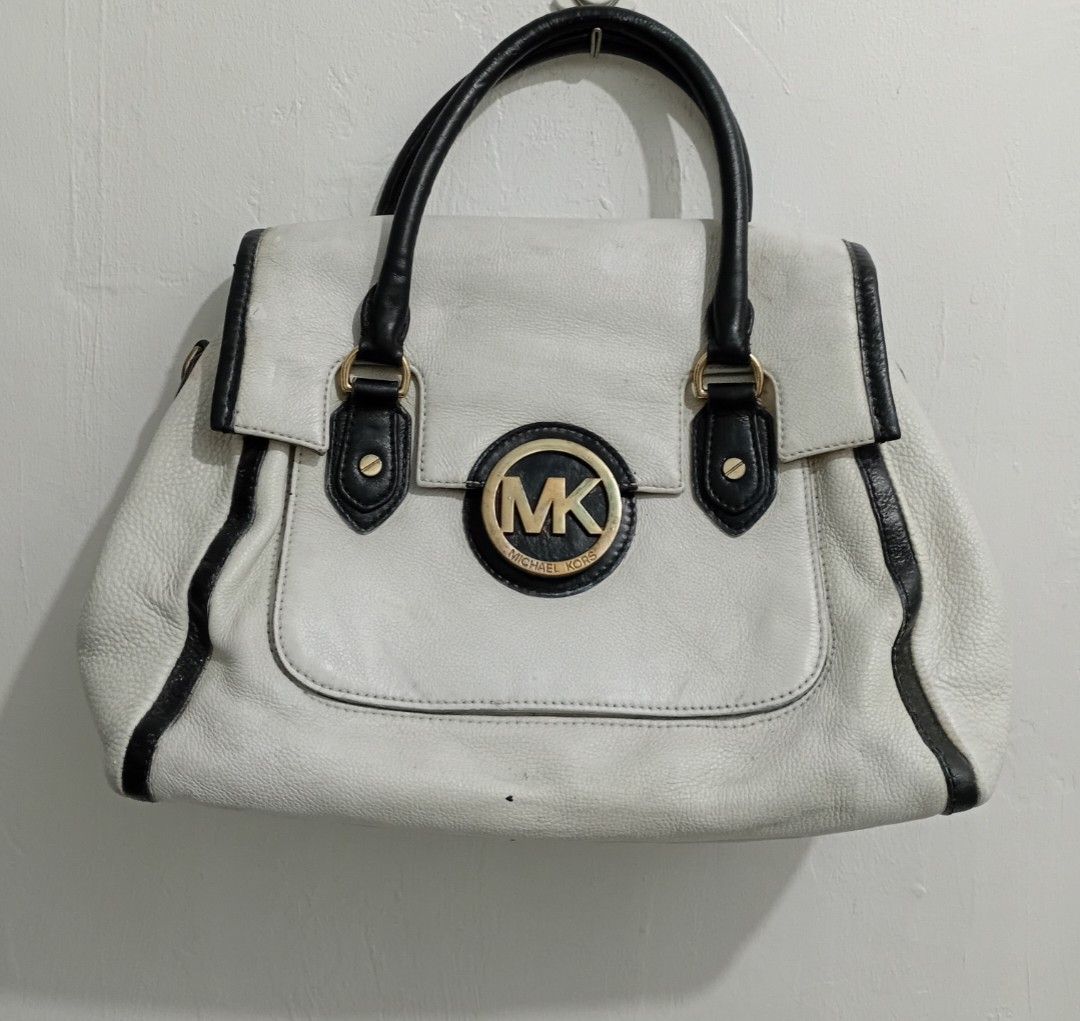 Michael Kors Off White Leather Satchel Handbag (Category: Luxury Bags & Wallets) located in Manila. Submitted by eriiicaspage (Listing ID 1460187822, Image 1). Description: PreOwned WellUsed Authentic Mk White leather handbag with black trim and handles Medium - Iconic Michael Kors (MK) logo on the front - Interior lining with repeating MK pattern - Ample space for your essentials - A timeless Michael Kors design Sign of Used Condition sa Leather