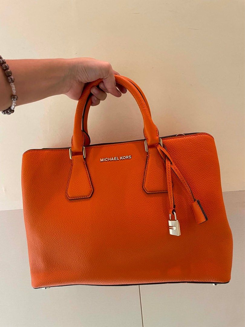 Michael Kors Orange Leather Satchel Bag (Category: Luxury Bags & Wallets) located in Manila. Submitted by thevintagebow (Listing ID 1460198655, Image 1). Description: Pop of color: Michael Kors Orange Pebbled Leather Satchel! 🍊 Add a gorgeous burst of energy to your closet with this vibrant, structured satchel. Crafted from supple orange pebbled leather with sleek silver-tone hardware, a secure top-zip closure, and an elegant hanging padlock cha
