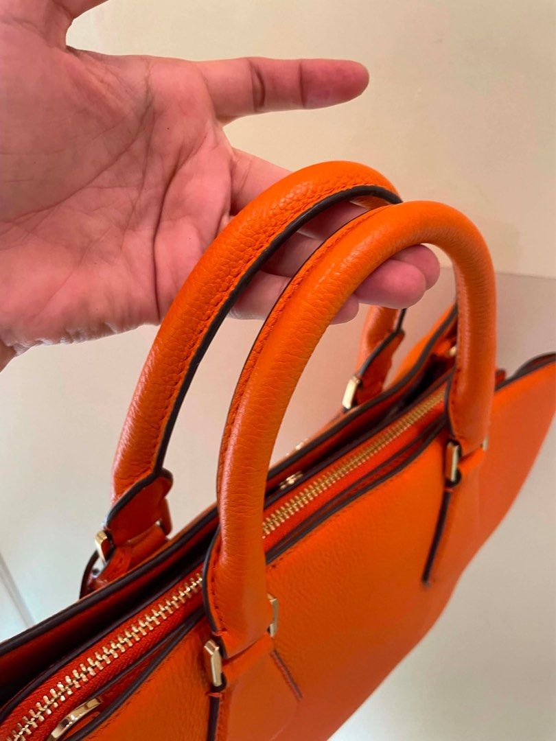 Michael Kors Orange Leather Satchel Bag (Category: Luxury Bags & Wallets) located in Manila. Submitted by thevintagebow (Listing ID 1460198655, Image 3). Description: Pop of color: Michael Kors Orange Pebbled Leather Satchel! 🍊 Add a gorgeous burst of energy to your closet with this vibrant, structured satchel. Crafted from supple orange pebbled leather with sleek silver-tone hardware, a secure top-zip closure, and an elegant hanging padlock cha